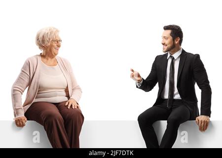 Uomo d'affari che parla con una signora anziana e seduto su un pannello isolato su sfondo bianco Foto Stock
