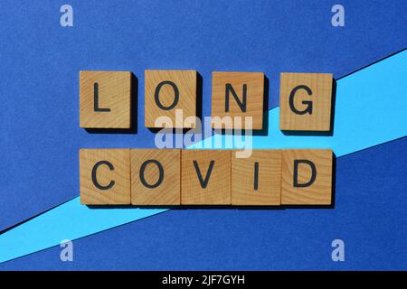 Lunga covid, parole in lettere di legno alfabeto isolato su sfondo blu Foto Stock