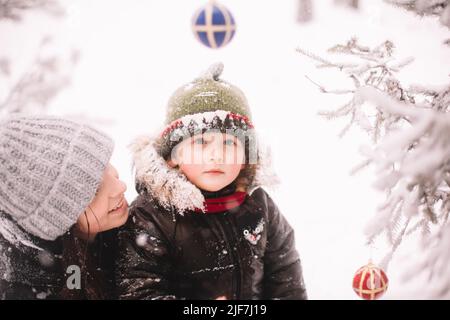Ritratto di madre e figlio felici sull'albero di natale all'aperto in inverno Foto Stock