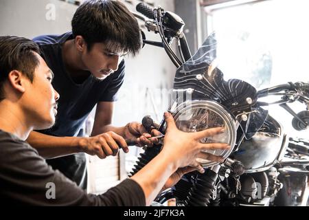 Meccanico che lavora sulla moto presso il negozio di biciclette su misura a Bangkok Foto Stock