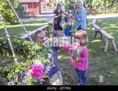 Midsummer in Svezia, genitori e bambini legano i fiori su grande minaccia in Malmkoping, Svezia Foto Stock