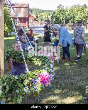 Midsummer in Svezia, genitori e bambini legano i fiori su grande minaccia in Malmkoping, Svezia Foto Stock