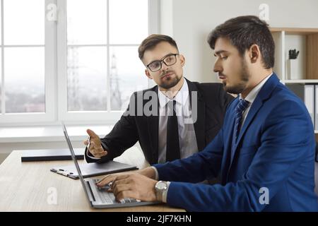 Due colleghi maschili discutono insieme il nuovo progetto mentre lavorano insieme in ufficio. Foto Stock