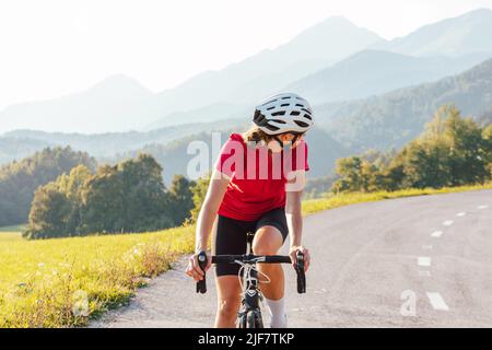 Giovane donna professionista bicyclist durante il ciclismo su strada sprint guardando dietro. Foto Stock