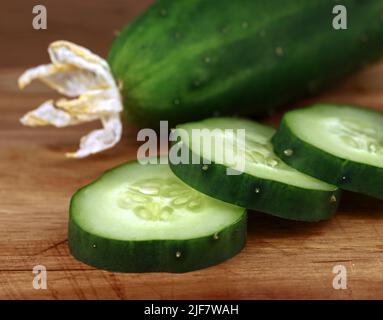 Primo piano di fette di cetriolo tagliate di un cetriolo all'aperto con fioritura di frutta secca, verdure fresche coltivate in casa Foto Stock