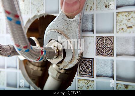 Accessori per impianti idraulici, tubo flessibile intrecciato in acciaio inox tubo per l'acqua per l'alimentazione di acqua calda e fredda a casa esce dal foro nel muro di casa in Foto Stock