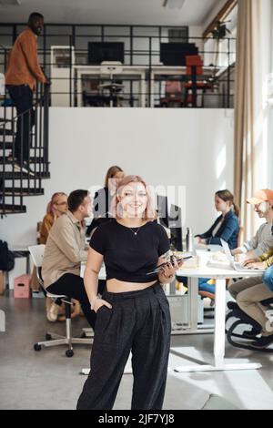 Ritratto di giovane donna d'affari con mano in tasca in piedi presso l'ufficio Tech start-up Foto Stock