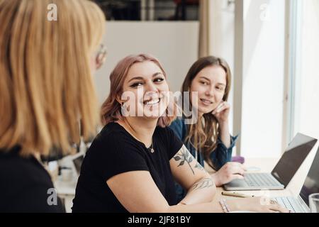 Imprenditori sorridenti che guardano un collega durante la riunione in ufficio Foto Stock