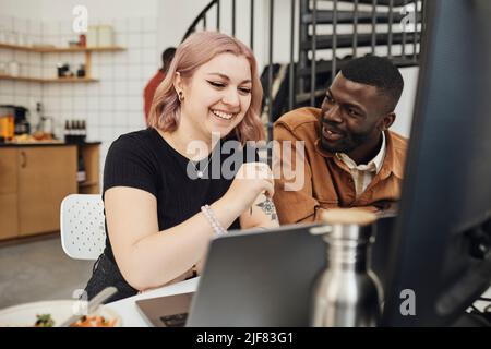 Programmatore di computer maschile discutere mentre si guarda felice collega femminile in start-up ufficio tecnico Foto Stock