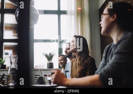 Donna d'affari sorridente per adulti di media età seduta con colleghi di sesso maschile nella sala riunioni Foto Stock