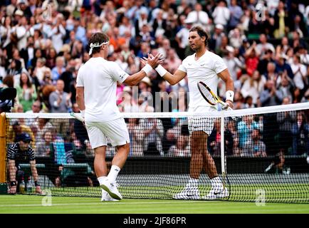 Il Rafael Nadal (a destra) della Spagna scuote le mani con Ricardas Berankis della Lituania dopo aver vinto la seconda partita dei singoli dei signori sul campo centrale durante il quarto giorno dei campionati di Wimbledon 2022 all'All England Lawn Tennis and Croquet Club, Wimbledon. Data foto: Giovedì 30 giugno 2022. Foto Stock