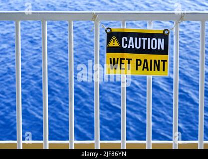 Cartello Wet Paint su ringhiere metalliche con il mare sullo sfondo. Nessuna gente. Foto Stock