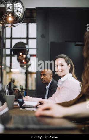 Ritratto di donna d'affari di adulto medio seduto con un computer portatile da colleghi nella sala riunioni Foto Stock
