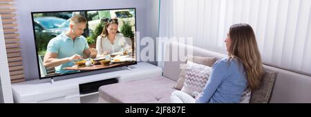 Donna matura seduti sul divano a guardare la televisione a casa Foto Stock