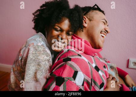 Felice donna hipster abbracciando gay uomo a casa Foto Stock
