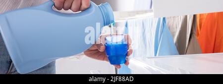 Close-up di mano di una persona versando detergente nel coperchio Foto Stock