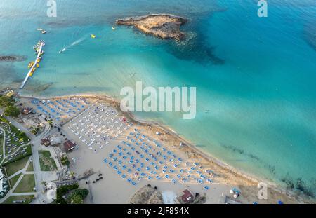 Ombrelloni in fila presso la spiaggia di fichi baie Protaras Cipro. Vacanze estive resort di vacanza. Foto Stock