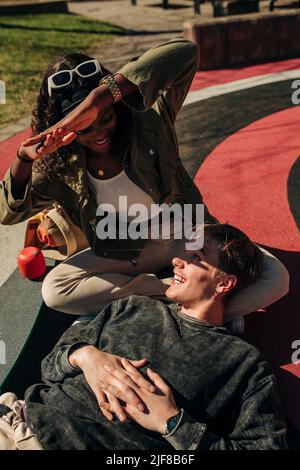 Donna che protegge il volto dell'uomo dalla luce del sole mentre si trova nel parco giochi Foto Stock