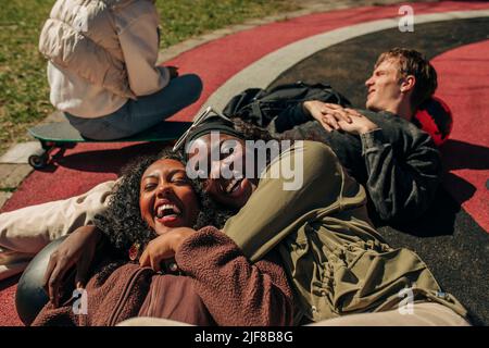 Buone giovani amiche sdraiate sul parco giochi Foto Stock
