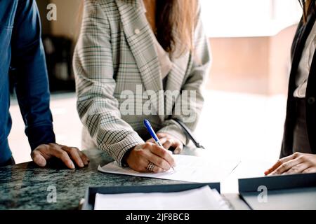 Metà sezione di coppia firma contratto con agente immobiliare in cucina Foto Stock