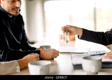 Agente immobiliare che dà la chiave alla coppia a casa Foto Stock