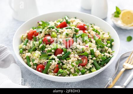 Insalata di tabbouleh. Insalata di tabouli con prezzemolo fresco, cipolle, pomodori, bulgur e fagioli verdi. Cibo vegetariano sano, dieta Foto Stock