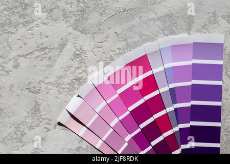 Catalogo tavolozza colori campioni viola, carte di selezione vernice su sfondo di pietra grigia Foto Stock