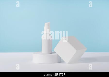 Crema cosmetica pompa metallica mockup bottiglia su sfondo blu su podio geometrico bianco. Confezione di prodotti di bellezza senza marchio lozione. Prodotto Foto Stock