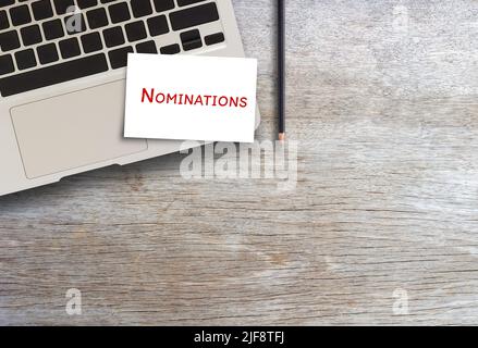 Scrittura a mano testo scrittura Nominations con computer portatile su legno table.concept significato azione di nomina Foto Stock