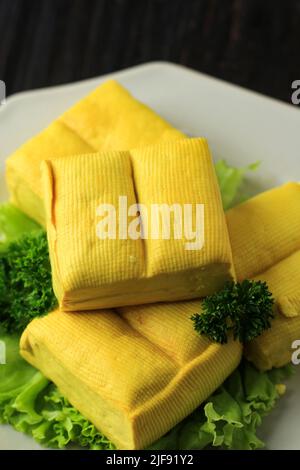 Tofu giallo morbido e sfondo tavola in legno, Asian Food Concept. Primo piano Foto Stock