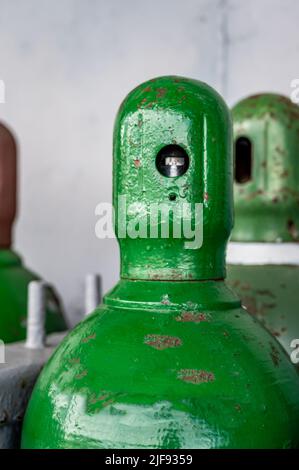 Le bombole di gas compresso vengono immagazzinate verticalmente fissate da una catena metallica e da un tappo metallico. Foto Stock