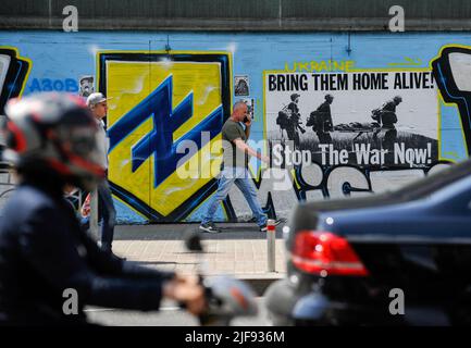 Kiev, Ucraina. 30th giugno 2022. Un uomo cammina davanti a un graffito raffigurante il simbolo del Battaglione Azov e un poster che dice: "Portali a casa vivi! Stop the war now' nel centro di Kyiv. La Russia ha invaso l'Ucraina il 24 febbraio 2022, scatenando il più grande attacco militare in Europa dalla seconda guerra mondiale Credit: SOPA Images Limited/Alamy Live News Foto Stock