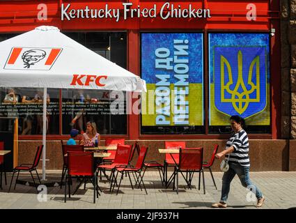 Kiev, Ucraina. 30th giugno 2022. Una donna passa accanto ad un ristorante fast food KFC nella finestra di cui il mantello di armi ucraino e l'iscrizione sono visibili "insieme alla vittoria" in mezzo all'invasione russa dell'Ucraina. (Foto di Sergei Chuzavkov/SOPA Images/Sipa USA) Credit: Sipa USA/Alamy Live News Foto Stock