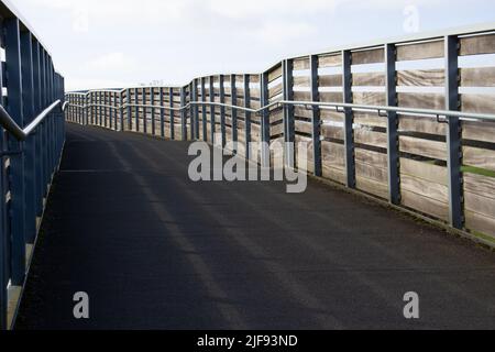 shared-use path up to a bridge in morning shadow and a blue sky with white clouds Foto Stock