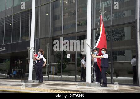 I lavoratori conducono una bandiera che alza in un edificio vicino al sito della cerimonia di consegna di Hong Kongs anniversario. Il leader cinese si trova nella città della RAS per partecipare alla cerimonia del 25th per l'anniversario della consegna, così come al giuramento di Hong Kongs nuovo amministratore delegato, John Lee Foto Stock