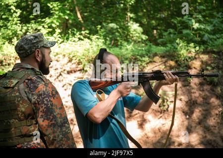 Un uomo civile ucraino si sta allenando per sparare una mitragliatrice AKM durante la guerra dell'Ucraina con la Russia Foto Stock