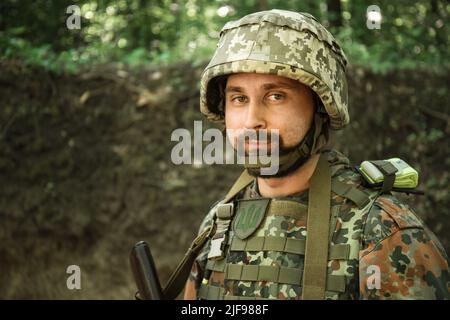 Ritratto di un uomo militare ucraino con un fucile d'assalto Kalashnikov nelle sue mani Foto Stock