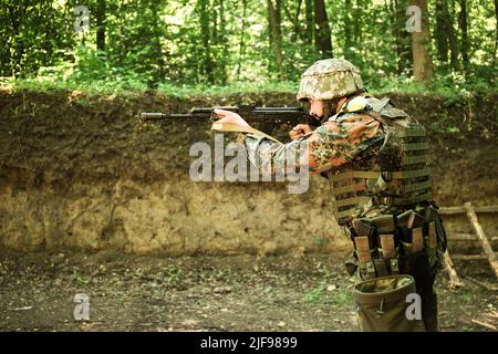 Ritratto di un uomo militare ucraino con un fucile d'assalto Kalashnikov nelle sue mani Foto Stock