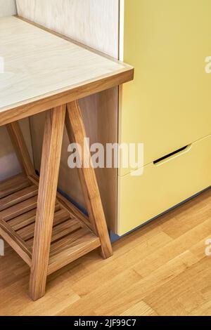 Frammento di tavolo per bambini con armadio in legno compensato e legno massello di quercia vicino a mobile giallo. Mobili in legno per il primo piano interno della camera da letto Foto Stock