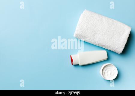 Boccetta per shampoo cosmetico con asciugamani su un tavolo colorato. Sfondo bagno, accessori per la cura delle mani e del corpo. Foto Stock