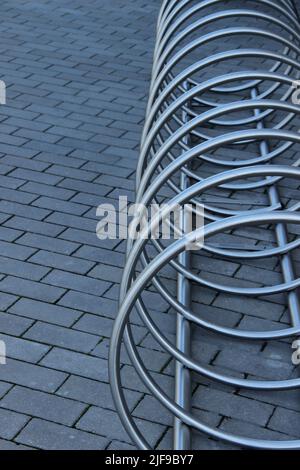 Portabiciclette in acciaio inox. Il moderno parcheggio per biciclette fa da sfondo astratto. Foto Stock