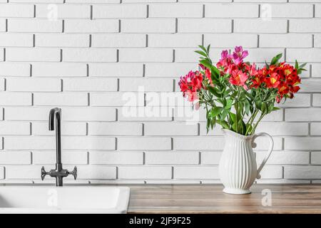 Vaso con bellissimi fiori di alstroemeria vicino al lavandino Foto Stock