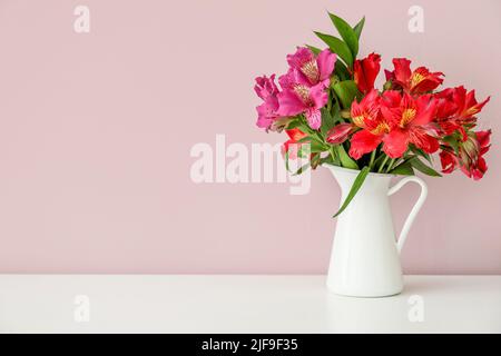 Vaso con bouquet di bellissimi fiori di alstroemeria vicino a pareti colorate Foto Stock