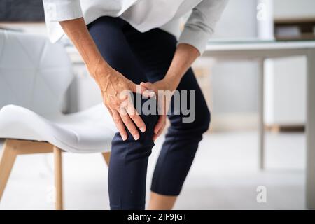 Donna che soffre di dolore al ginocchio mentre cerca di stare in piedi Foto Stock