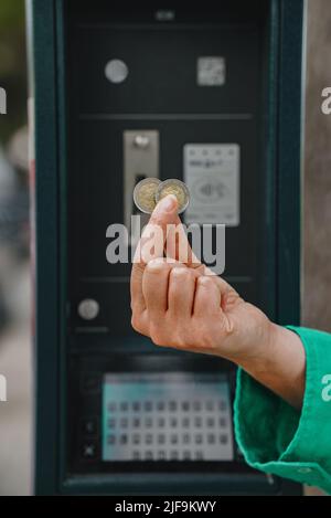 Donna che detiene monete in euro di fronte al parcheggio auto. Foto Stock