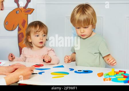 I bambini piccoli ragazzo e una ragazza hanno messo insieme le forme sul tavolo Foto Stock