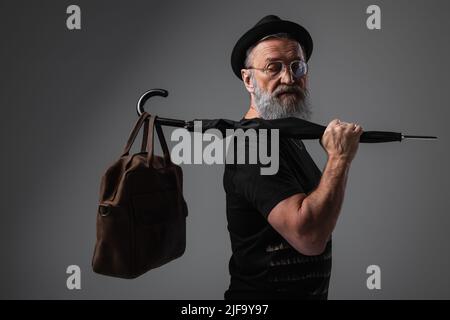 elegante uomo anziano in berretto con ombrello in pelle grigio Foto Stock