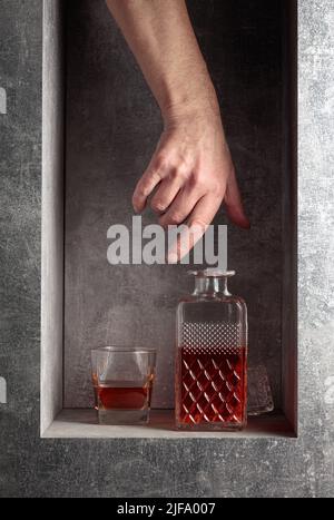 Sbraccio a mano per un decanter di whiskey. Un'immagine concettuale sul tema delle bevande costose. Foto Stock