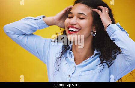 Closeup bella donna di moda gara mista sorridendo con gli occhi chiusi contro un muro di sfondo giallo in città. Giovane ispanica donna in cerca Foto Stock