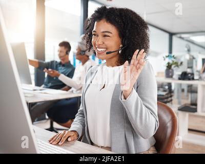 Felice agente di telemarketing misto del call center di gara che salutano durante una riunione virtuale tramite videochiamata su un computer in ufficio. Consulente femminile Foto Stock